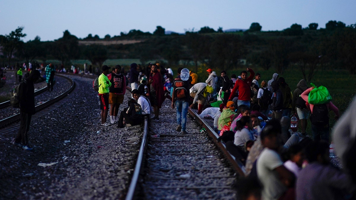 People sitting, waiting on train tracks