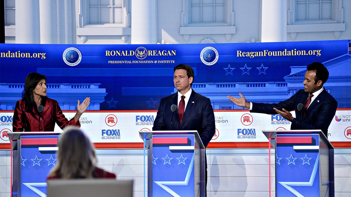 Nikki Haley (L), Ron DeSantis (C) and Vivek Ramaswamy (R) stand on debate state