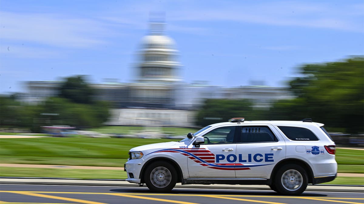 police car passing US Capitol