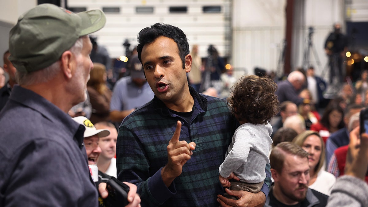 Ramaswamy holds his child while talking to Iowa voters