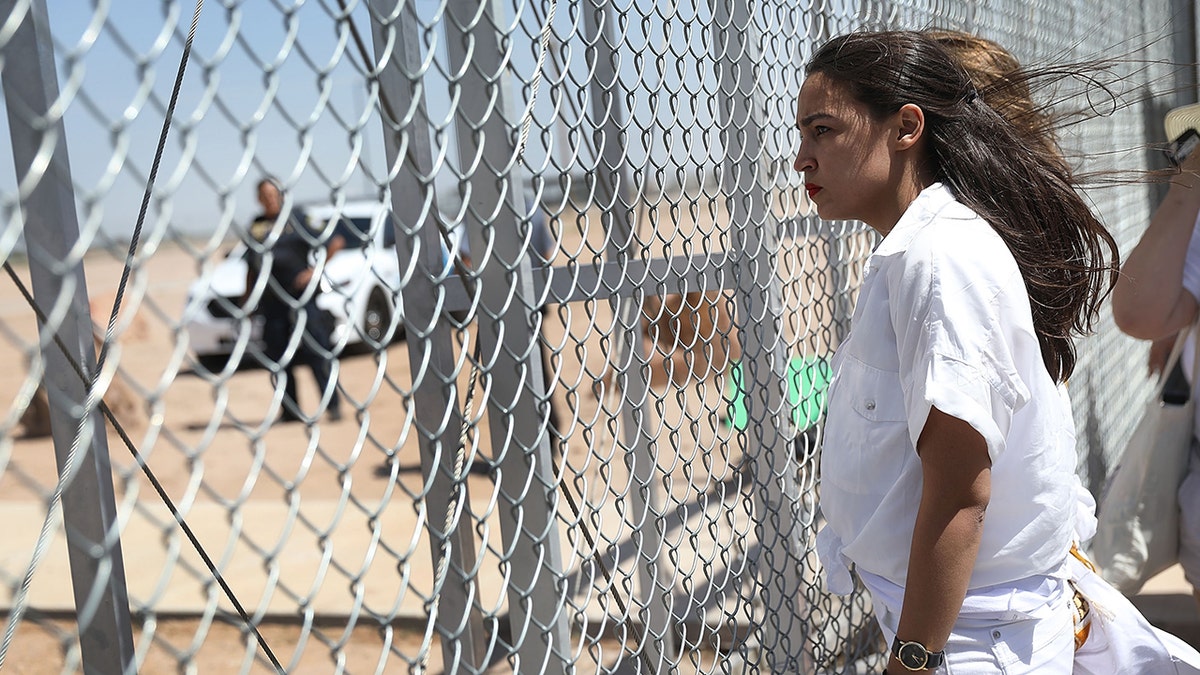 AOC standing at a fence