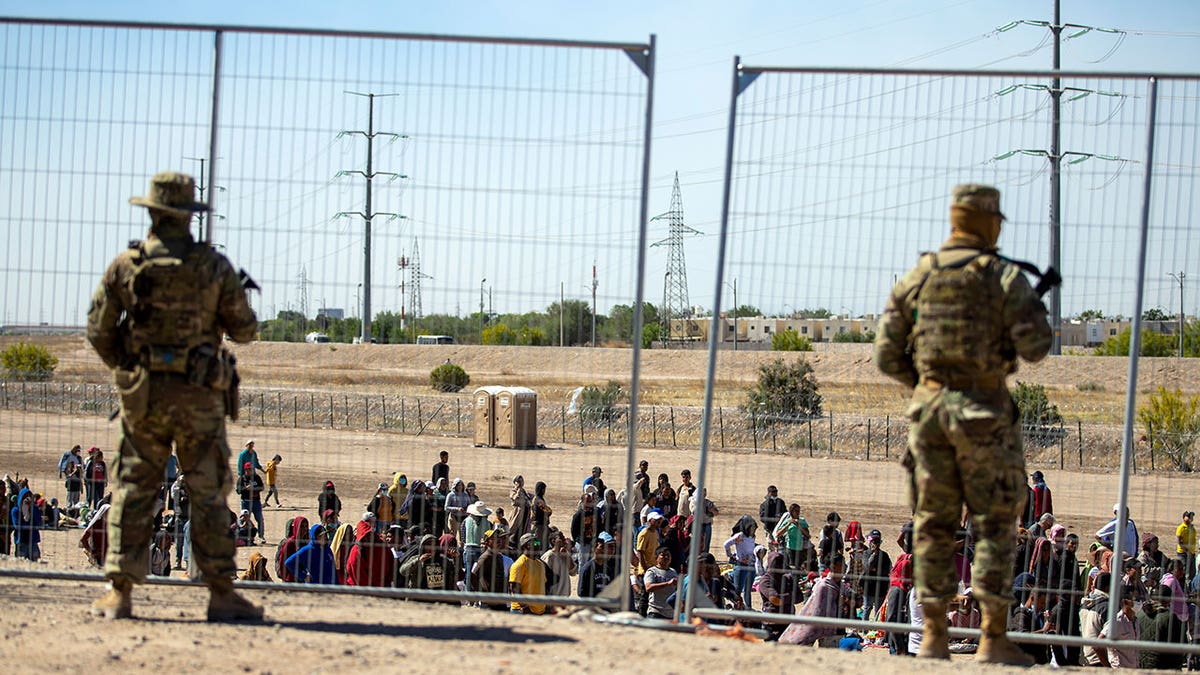 Border Patrol agents stand in front of gate