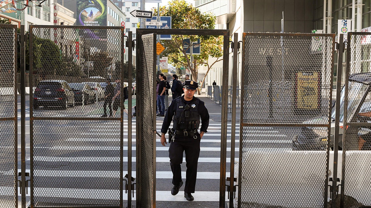 San Francisco police officer walks through metal fencing to APEC center
