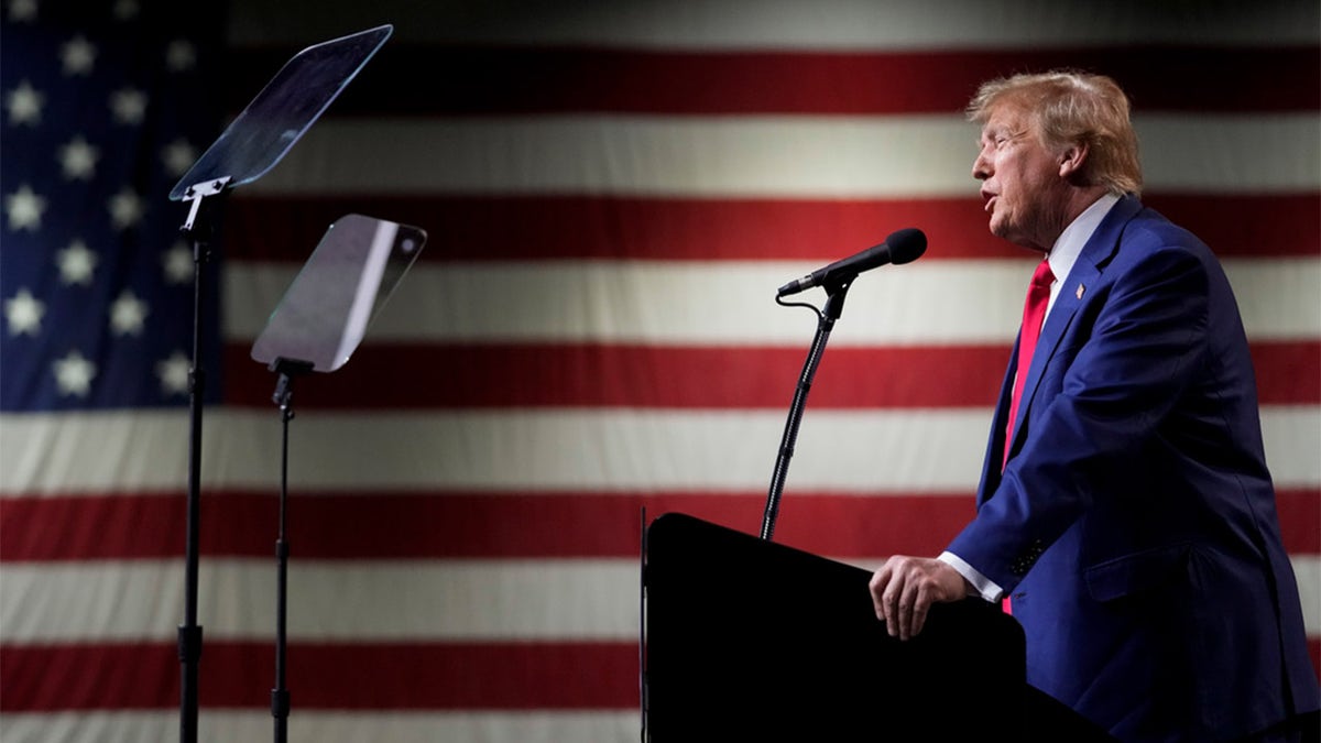 Donald Trump speaking in front of an American flag