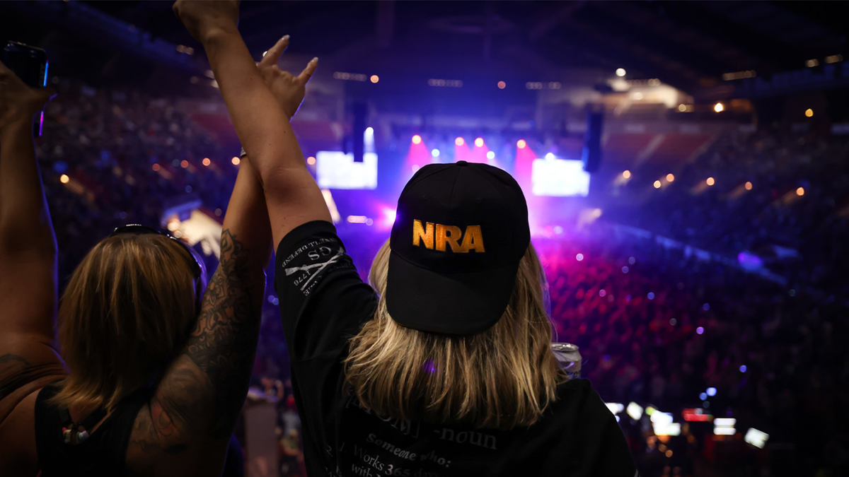 NRA concertgoers enjoy music as one wears NRA ballcap