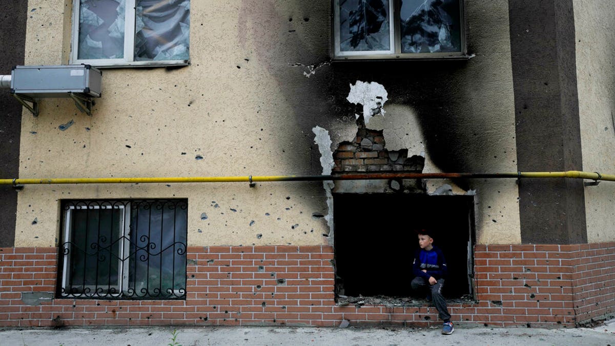 Boy sits in window of destroyed building