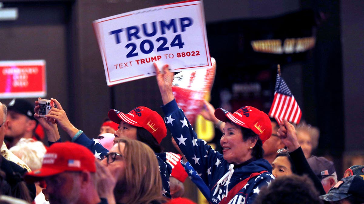A woman holds up a "Trump 2024" sign