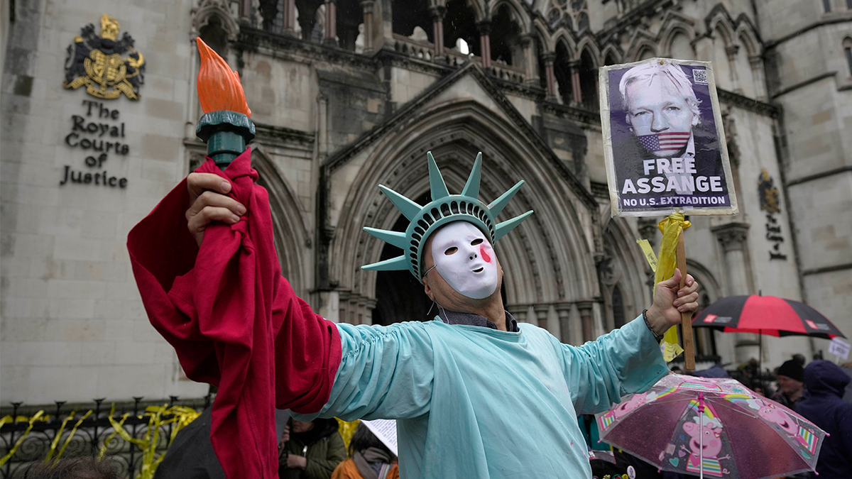 Assange supporters hold signs outside the High Court in London