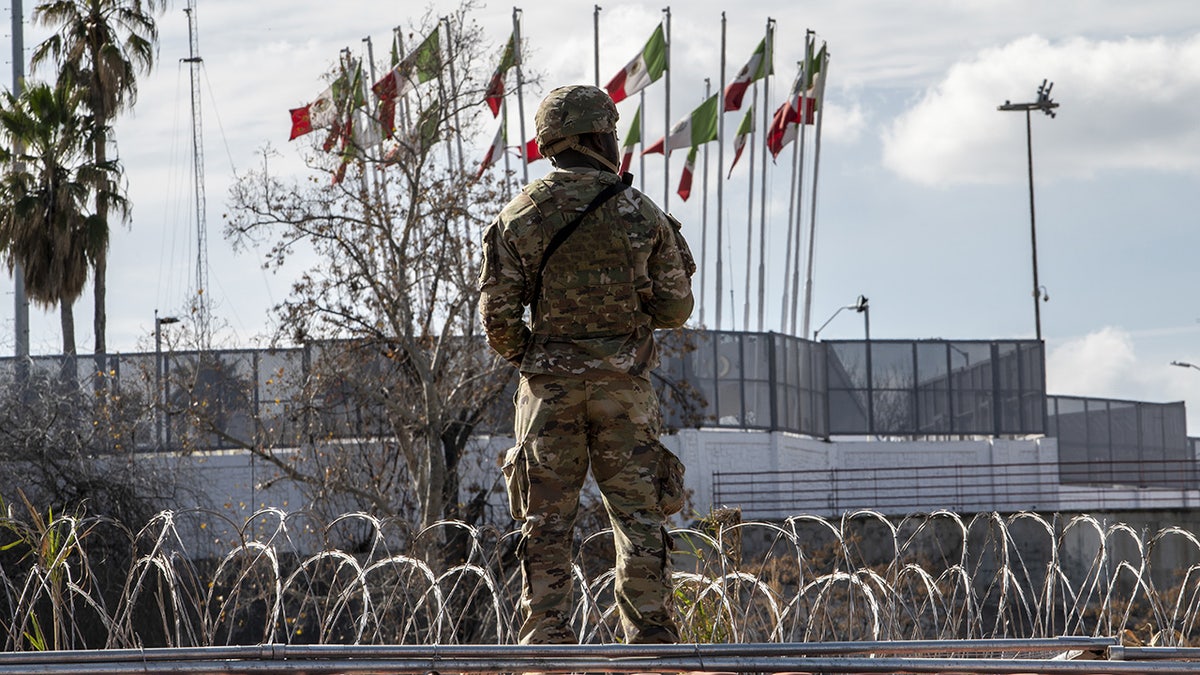 Texas National Guardsman stands on top of shipping container at Mexico border