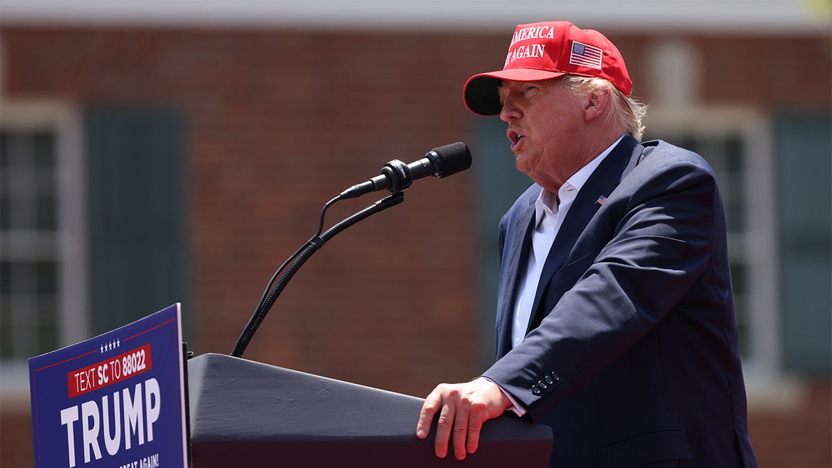 Donald Trump in red MAGA hat at lectern