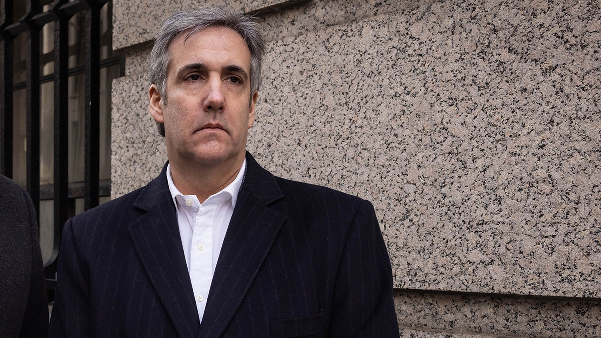 Michael Cohen in dark jacket frowning outside building