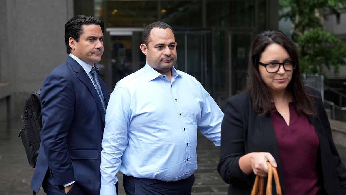 Wael Hana in blue shirt, center, leaves courthouse