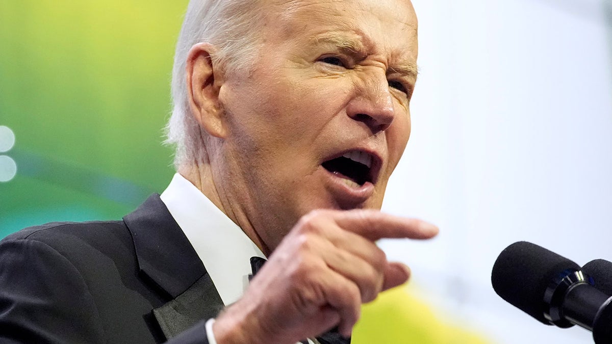 Biden points at gala while speaking through a mic