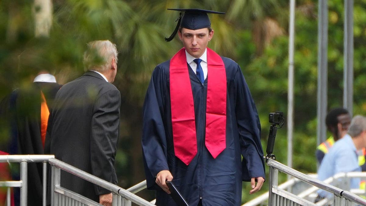 Barron Trump in cap and gown receives his diploma