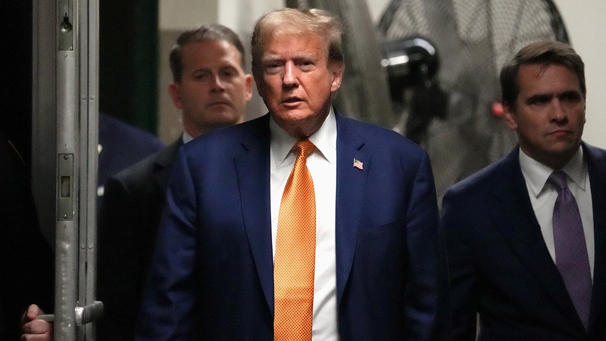 Donald Trump in courthouse hallway in orange tie
