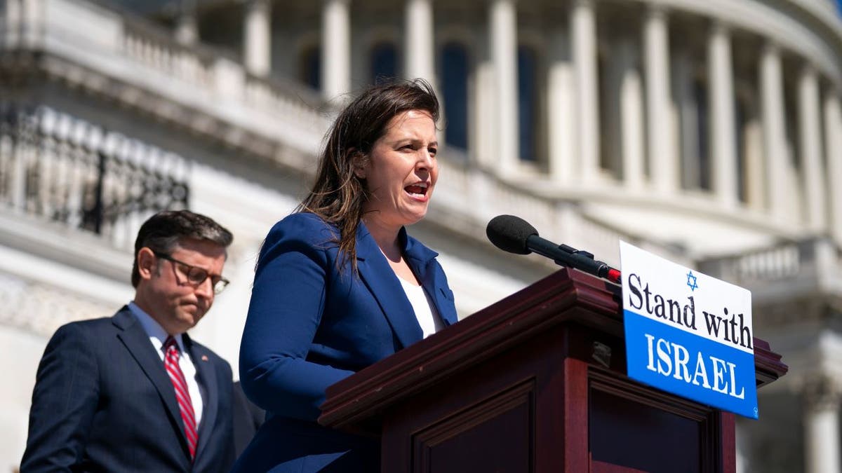 Stefanik speaking at podium with pro-Israel banner