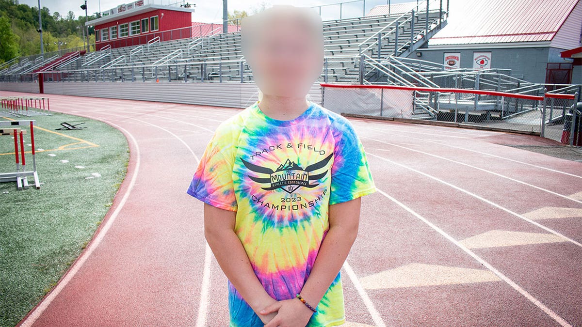 trans athlete with face blurred standing on track