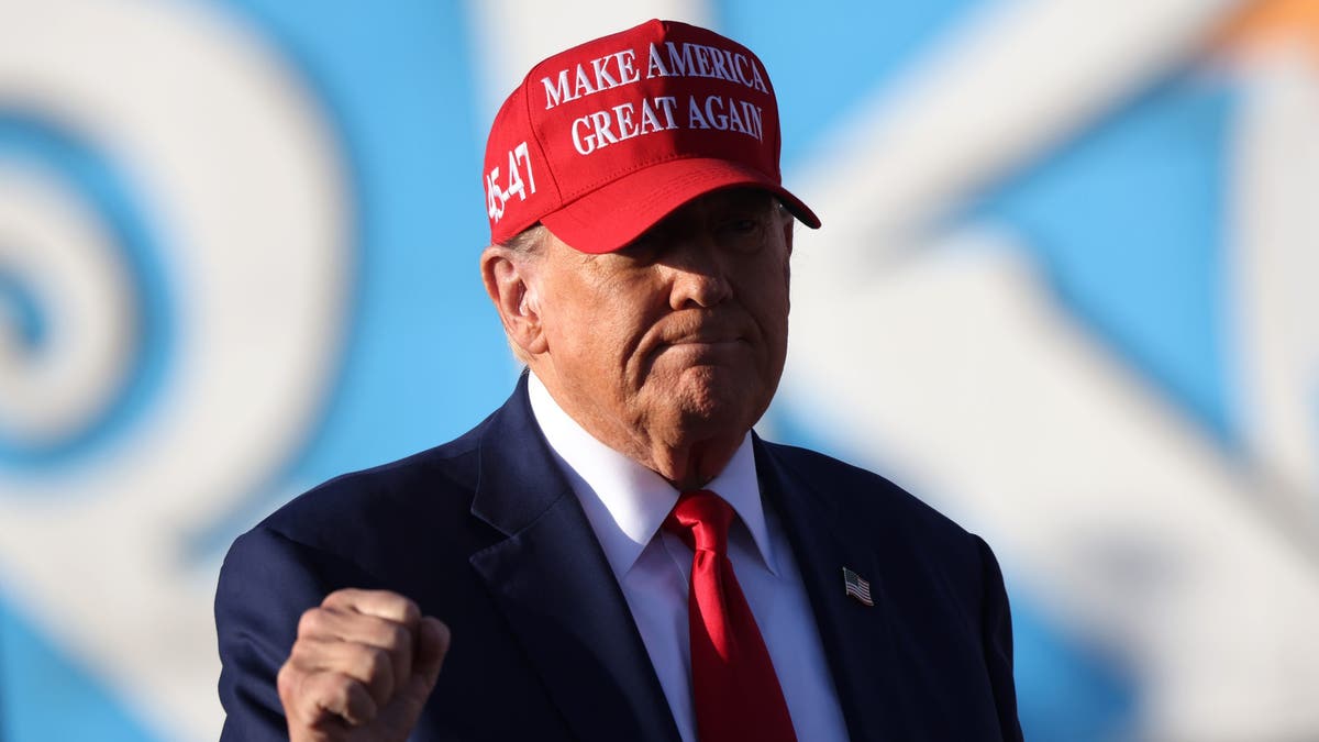 Trump at rally in red MAGA hat pumping fist