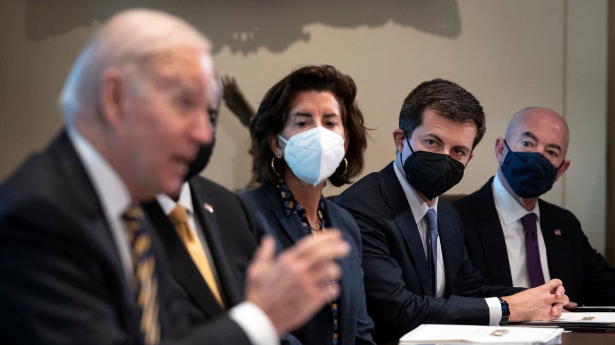 Transportation Secretary Pete Buttigieg listens as President Joe Biden speaks