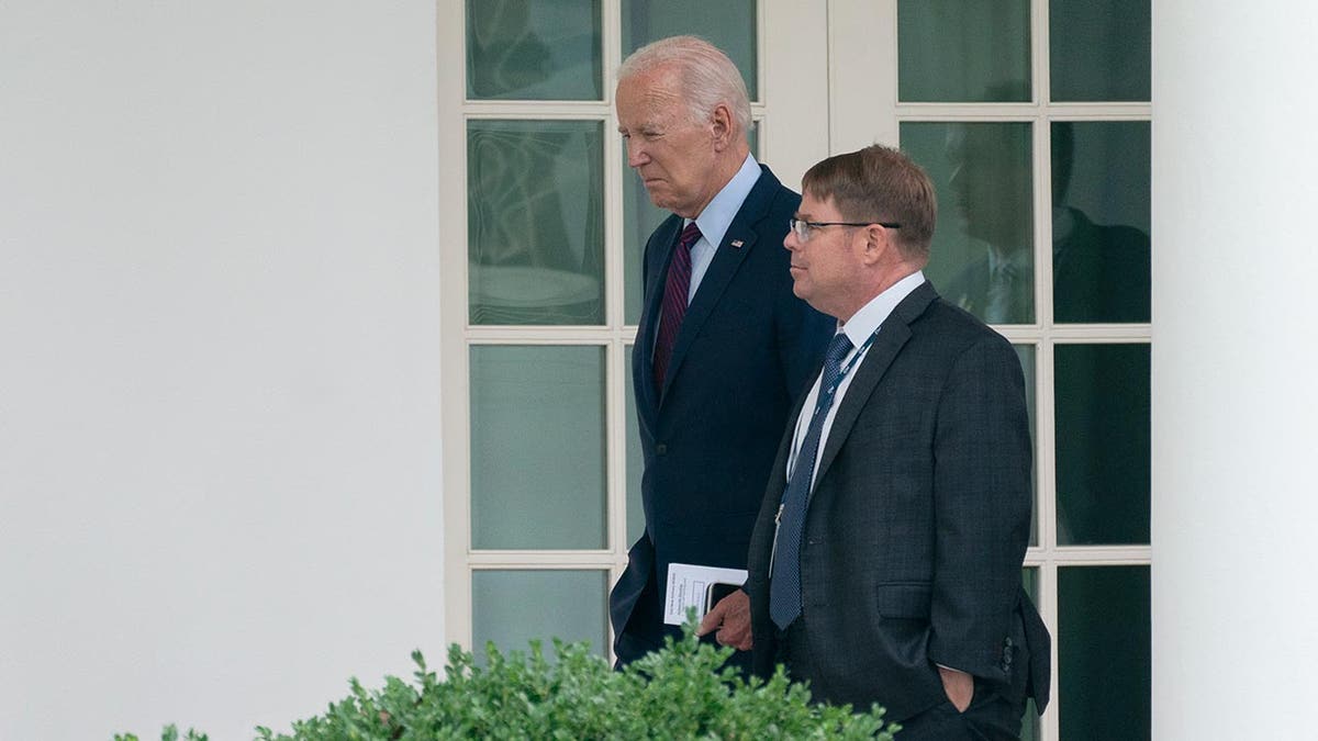 Biden and O'Connor walk along the side of the White House