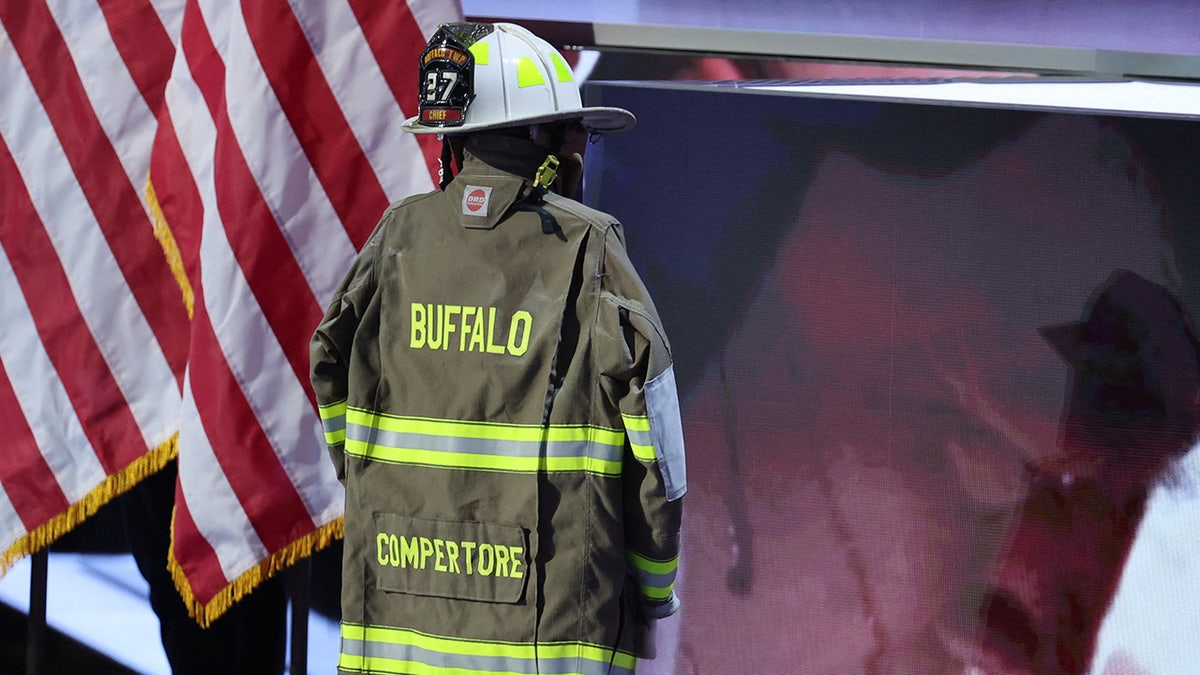 A turnout coat and helmet are pictured onstage as a picture of Republican presidential nominee and former U.S. President Donald Trumps attempted assassination is shown during his speech