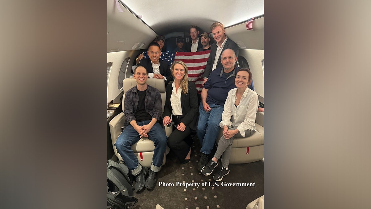 Evan Gershkovich, Alsu Kurmasheva, and Paul Whelan smile aboard an airplane after being released from Russian prison