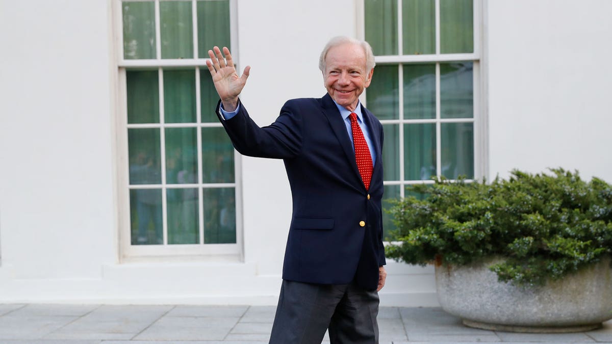 Joe Lieberman waves to members of the media as he leaves the West Wing