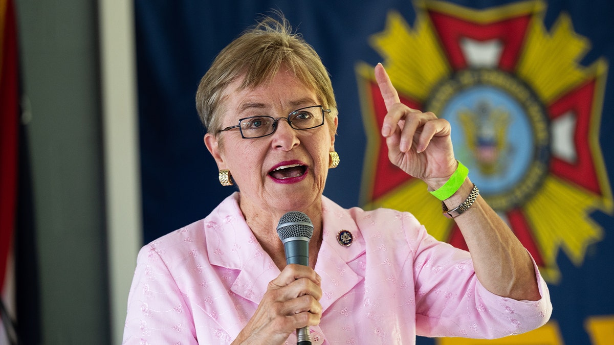 Marcy Kaptur holding microphone in right hand, left hand raised