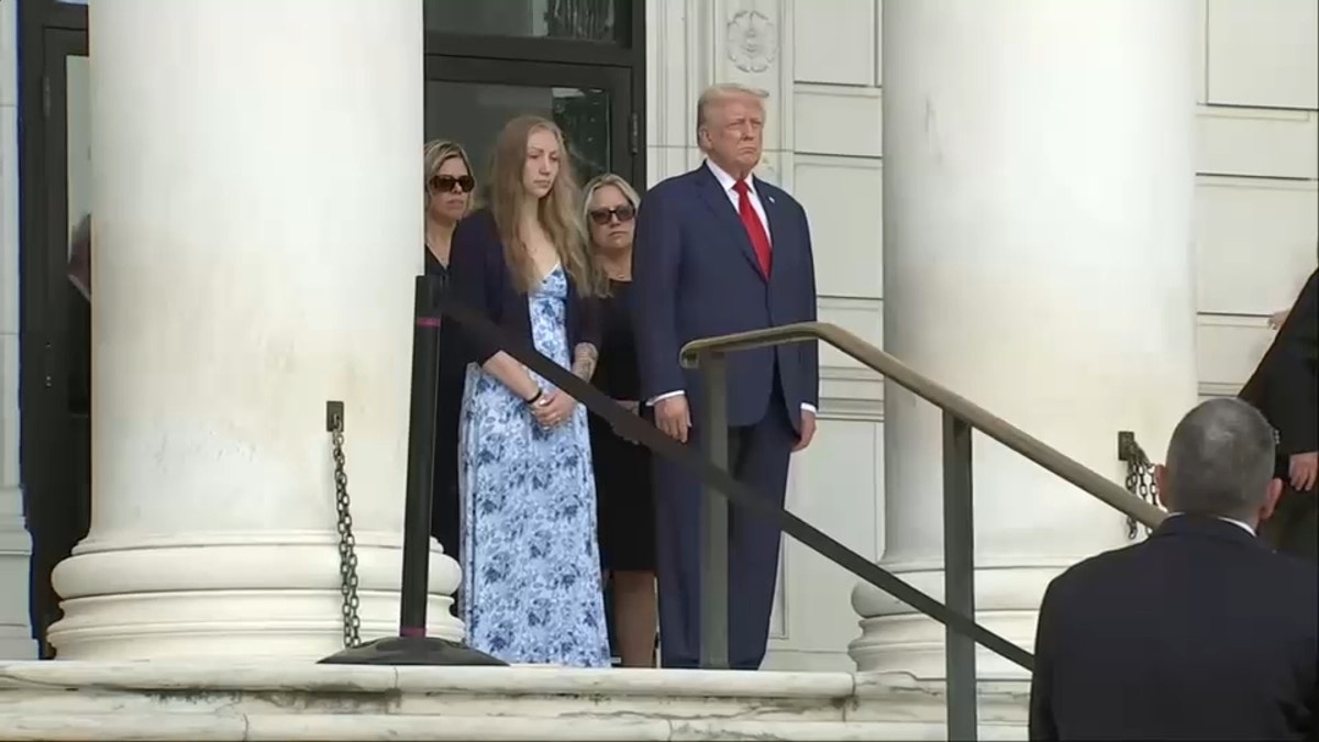 Trump stands on the steps with a young woman at the Arlington wreath laying ceremony