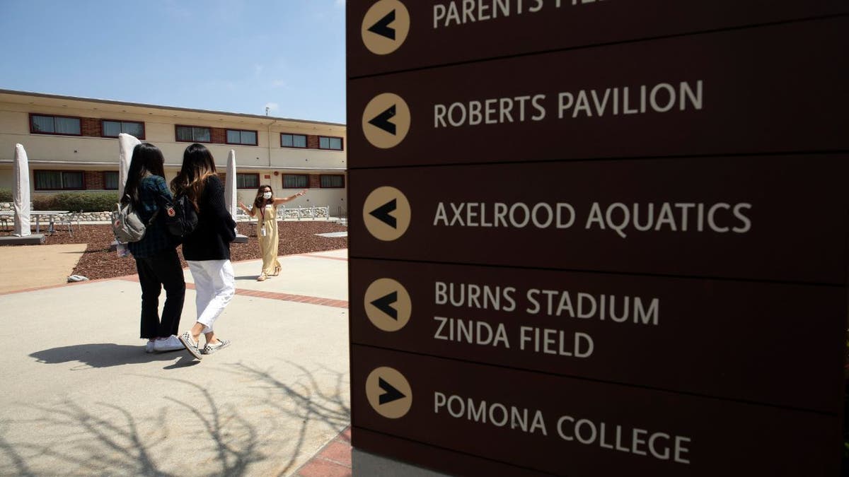 sign on college campus with students walking past