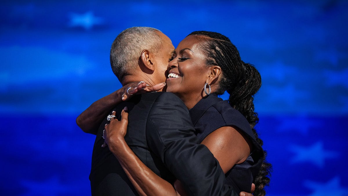 Obamas embrace on DNC stage