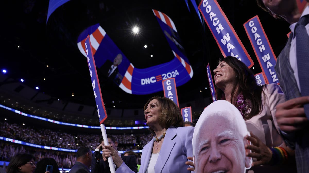 Former House Speaker Rep. Nancy holds a sign that says "Coach Walz" during the Democratic National Convention.