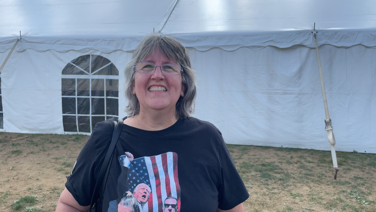 woman smiling in T-shirt with tent behind her