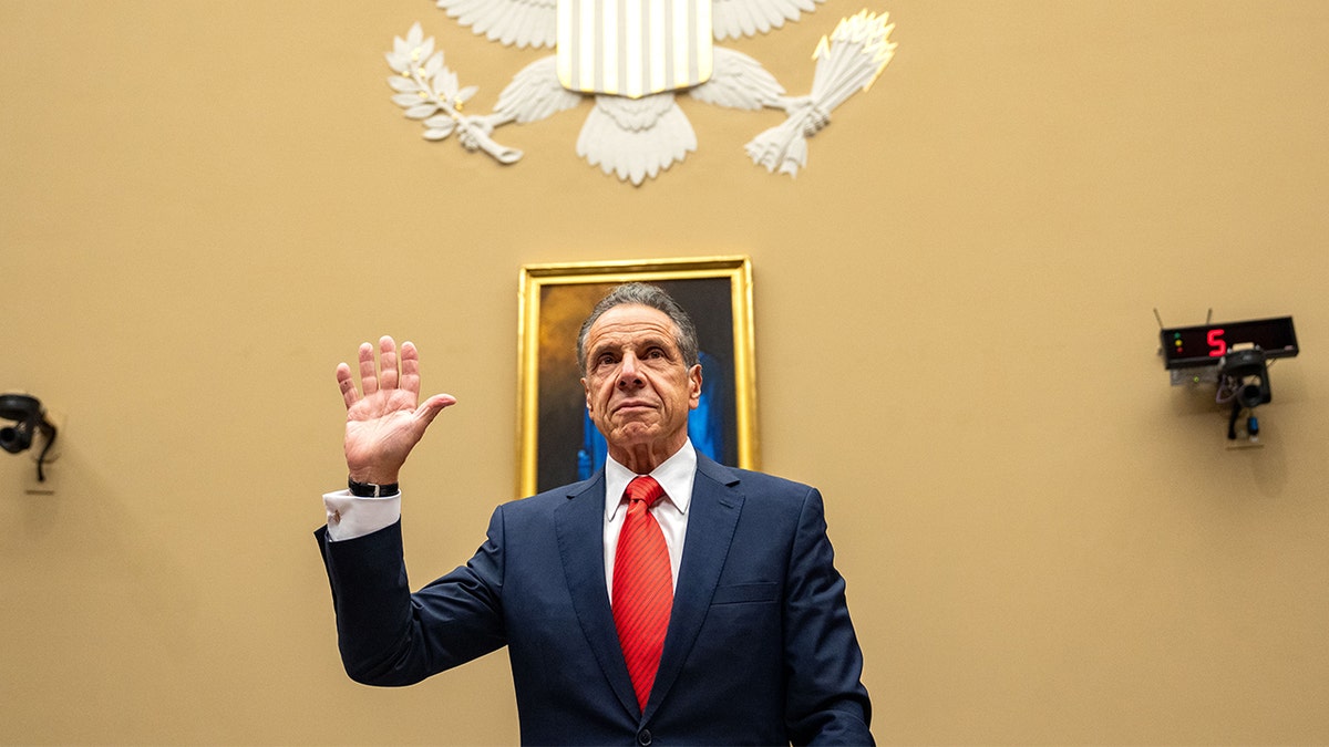 former NY Gov. Andrew Cuomo raises his hand to swear before testifying