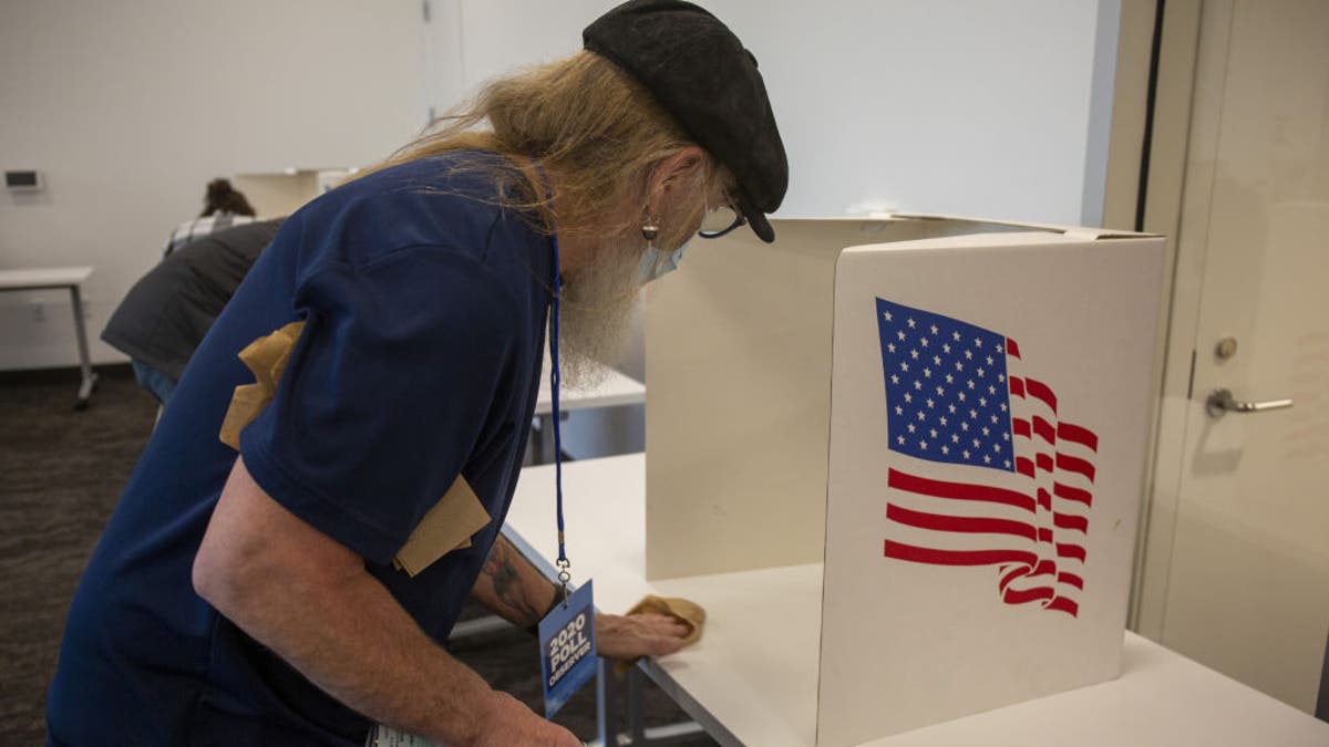 A volunteer sanitizes a voting booth at a polling location for the 2020 presidential election in Ankeny, Iowa.