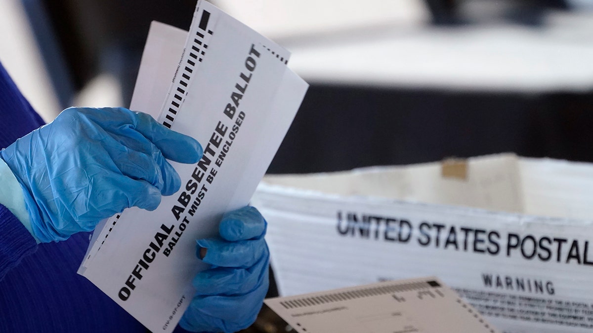 Absentee ballots held in gloved hand