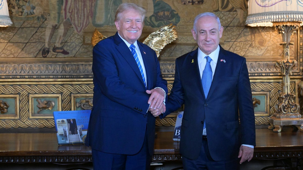 Former US President Donald Trump shakes hands with Israeli Prime Minister Benjamin Netanyahu as they pose for a photo within their meeting at Mar-a-Lago estate