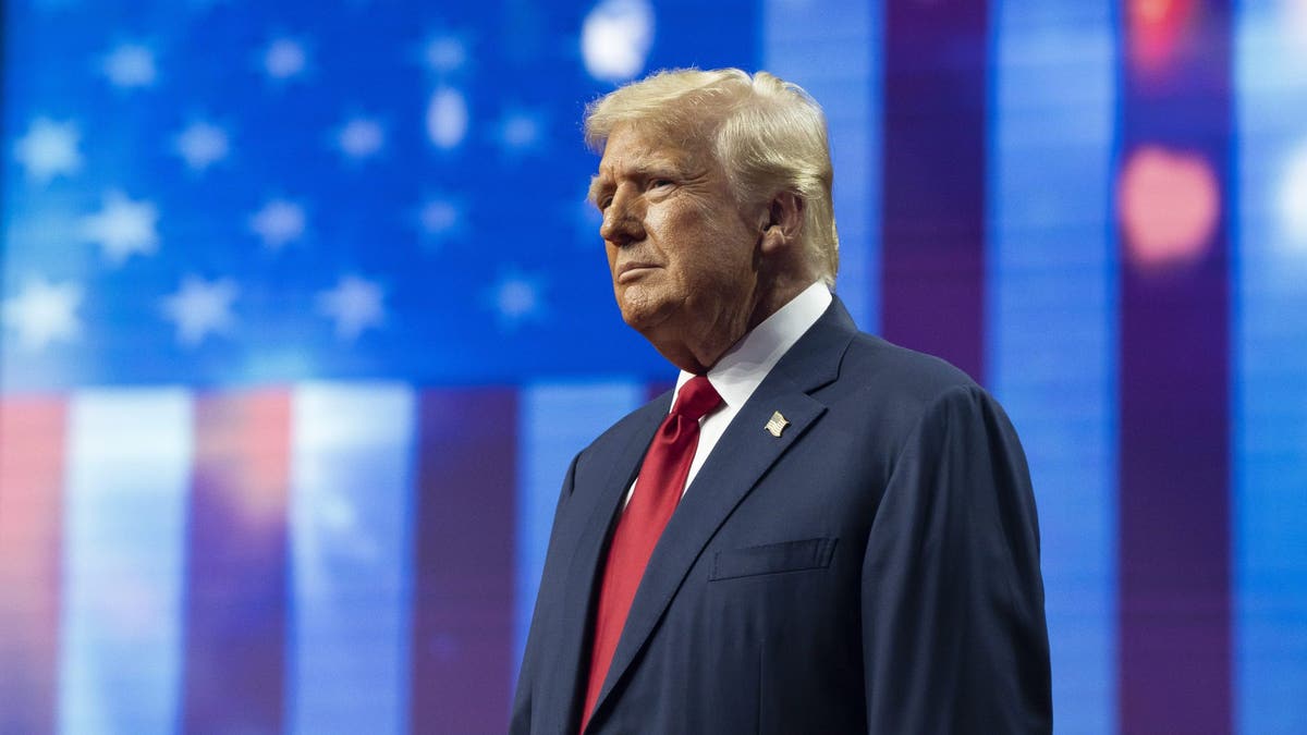 Trump on stage in front of a massive American flag