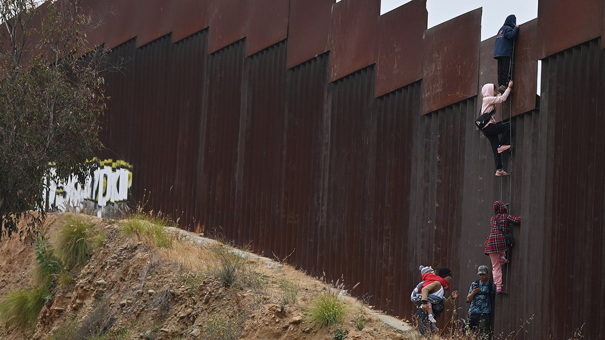 Migrants climb the wall