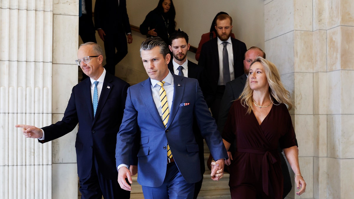 President-elect Donald Trump's nominee to be Secretary of Defense Pete Hegseth, center, and his wife Jennifer Rauchet walk through the Hart Senate Office building on Dec. 3, 2024 in Washington, D.C.