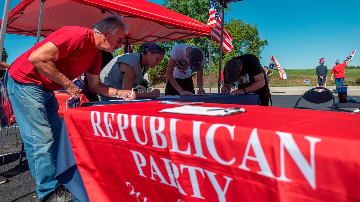 people signing forms at Republican Party table outside