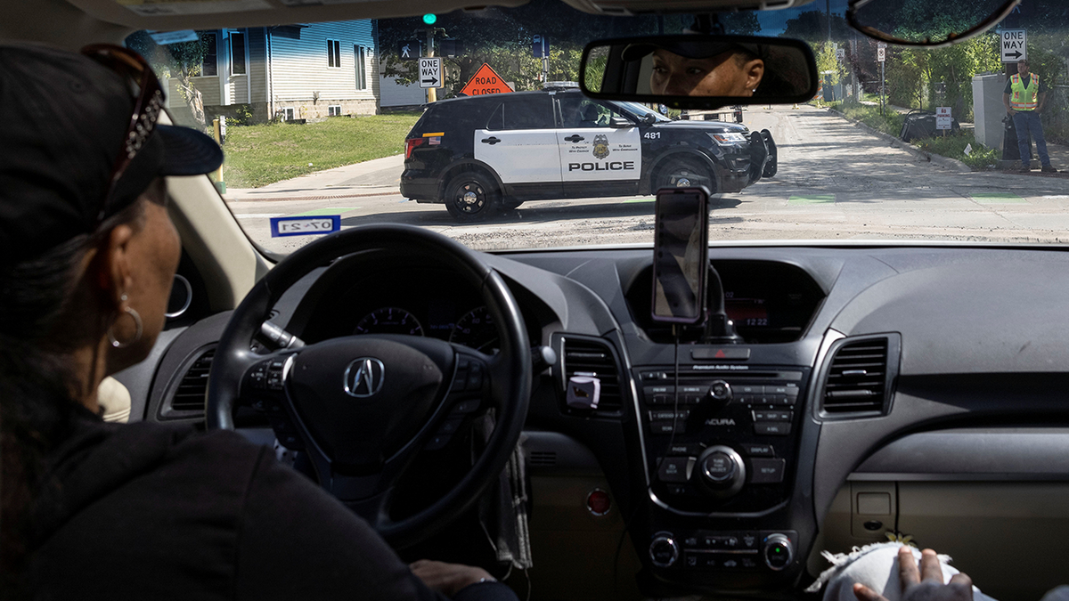 A local resident looks at a police vehicle driving along a street north of Minneapolis on Sept. 9, 2021.