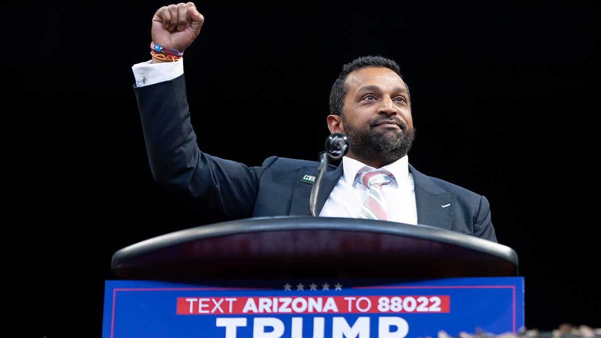 Kash Patel at Trump rally lectern, right arm raised