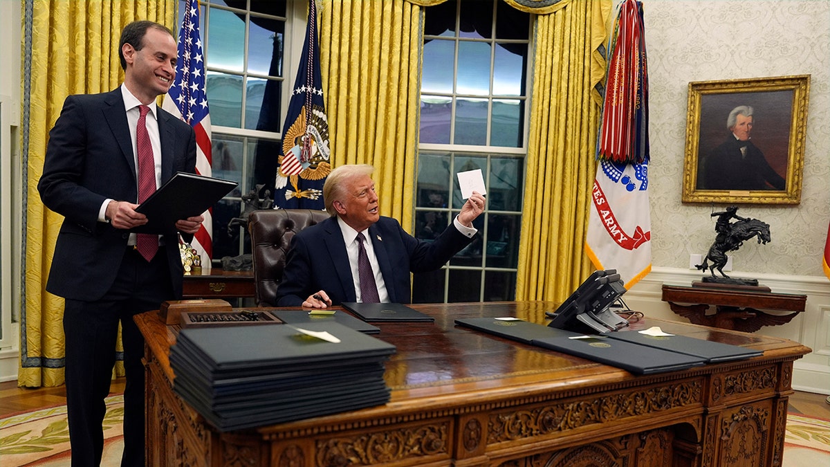 President Donald Trump holds up letter