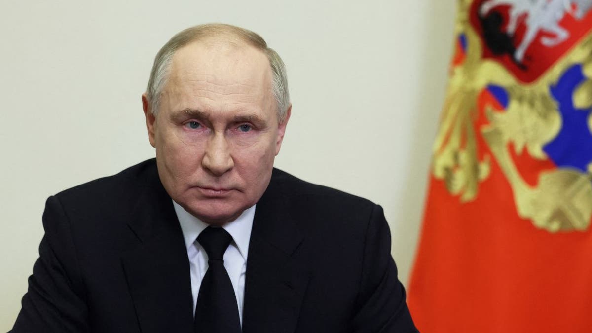 Putin frowning in closeup shot, flag behind him