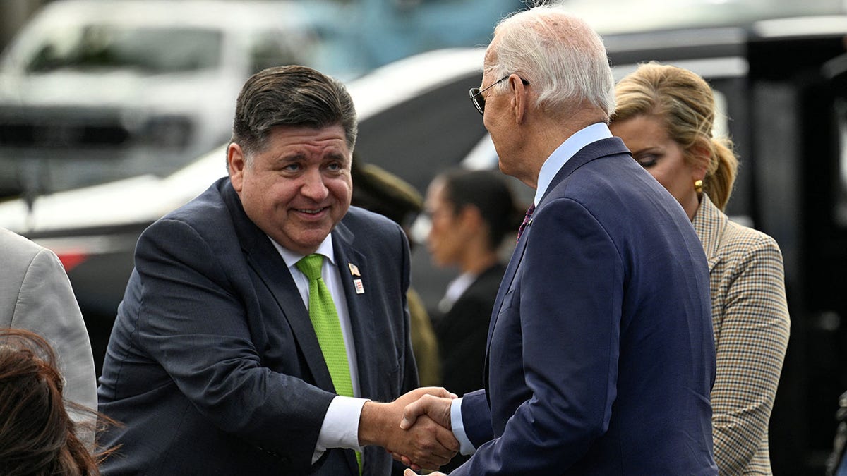 President Joe Biden, right, is greeted by Illinois Gov. JB Pritzker