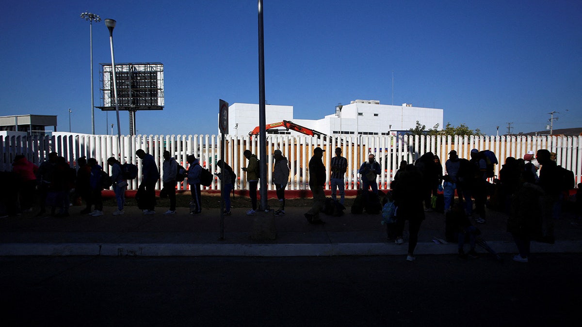 Migrants seeking asylum in the United States who previously requested an appointment on the CBP One Mobile application, are silhouetted as they queue at El Chaparral border crossing