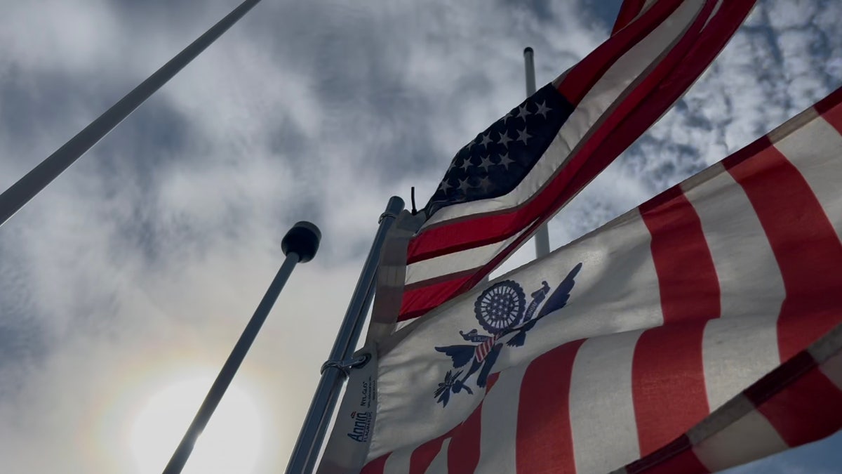 Strong winds blow American Flag and United States Coast Guard flag aboard a vessel on the Rio Grande 