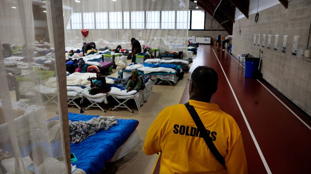 Meshach Little of Northill Wilkston Security Firm walks the perimeter of the main living area at the state's new emergency overflow shelter for migrants at the Melnea A. Cass Recreational Complex.