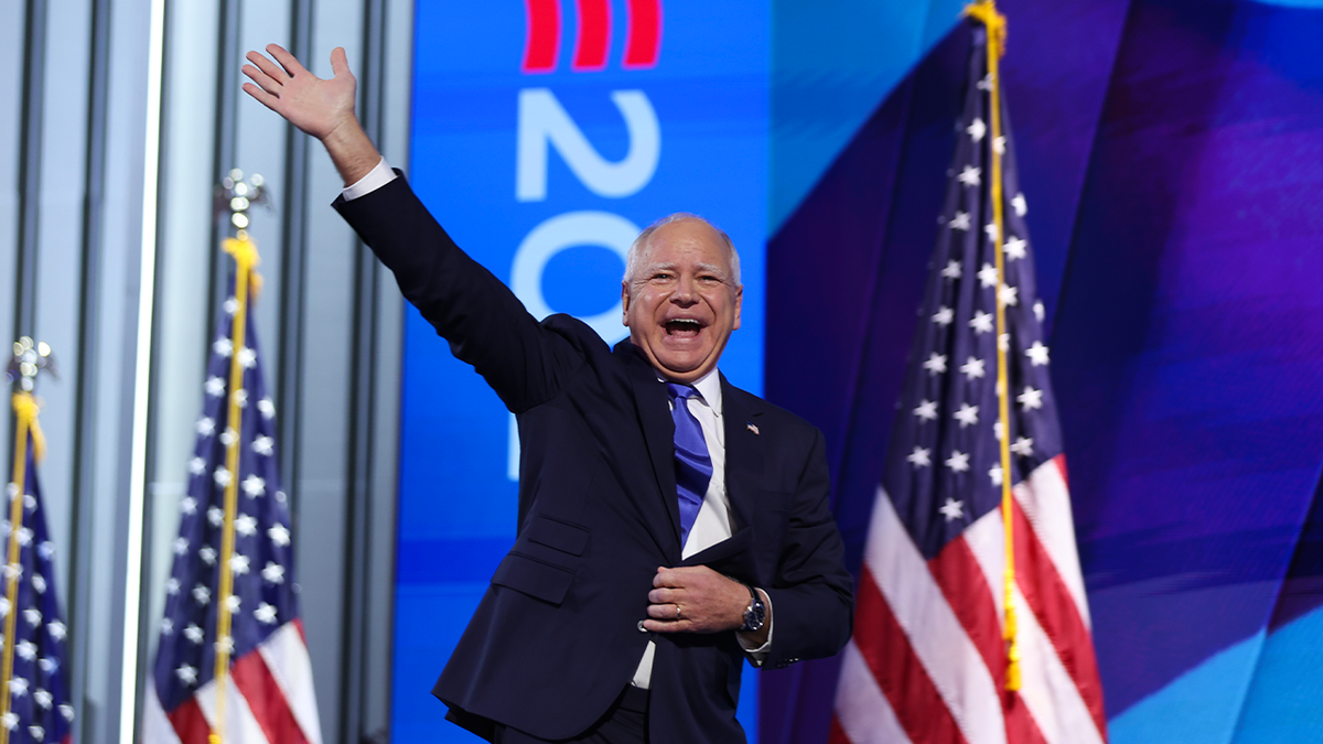 Gov. Tim Walz on stage at DNC, flags behind him